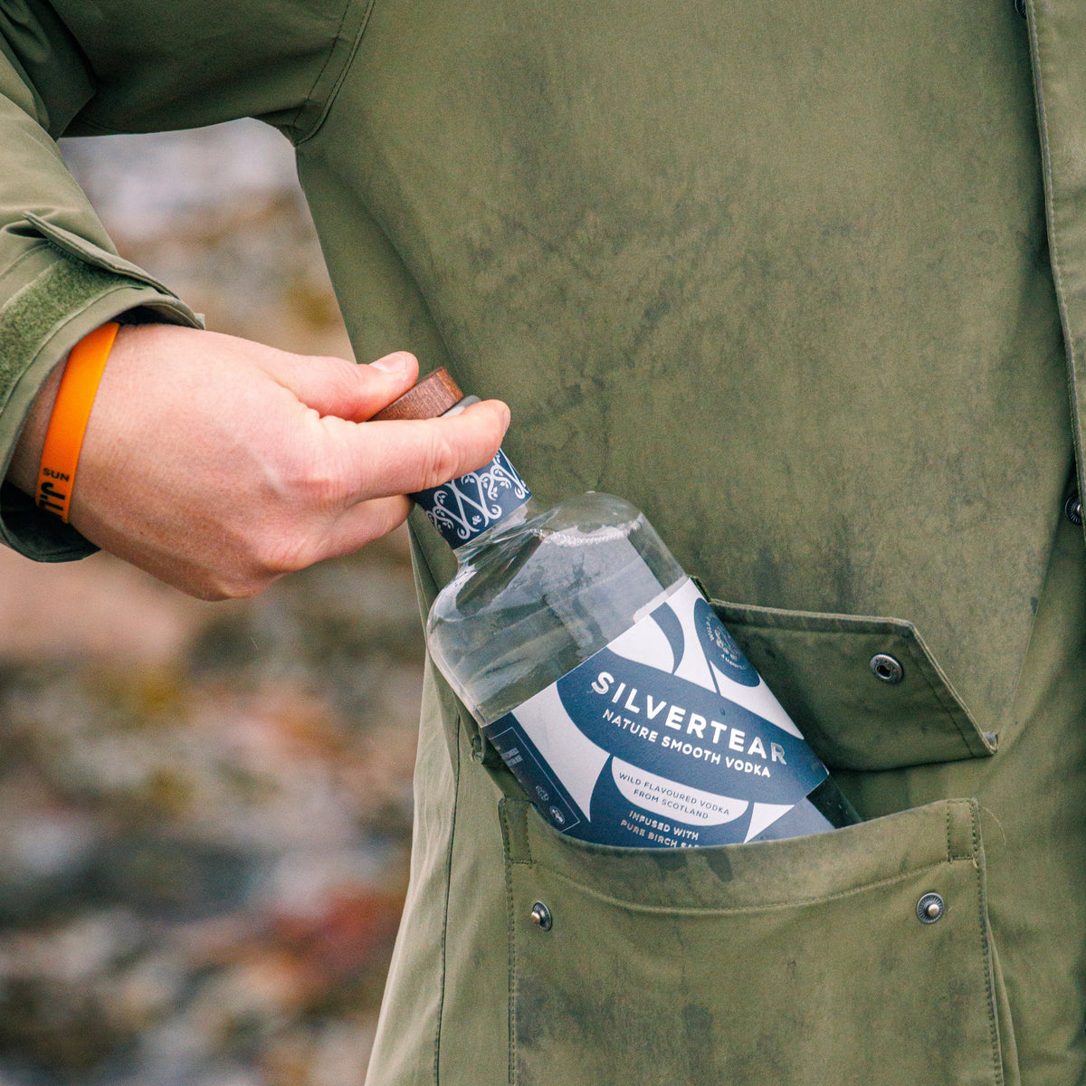 A bottle of Silvertear Nature vodka tucked into the pocket of a green waxed jacket
