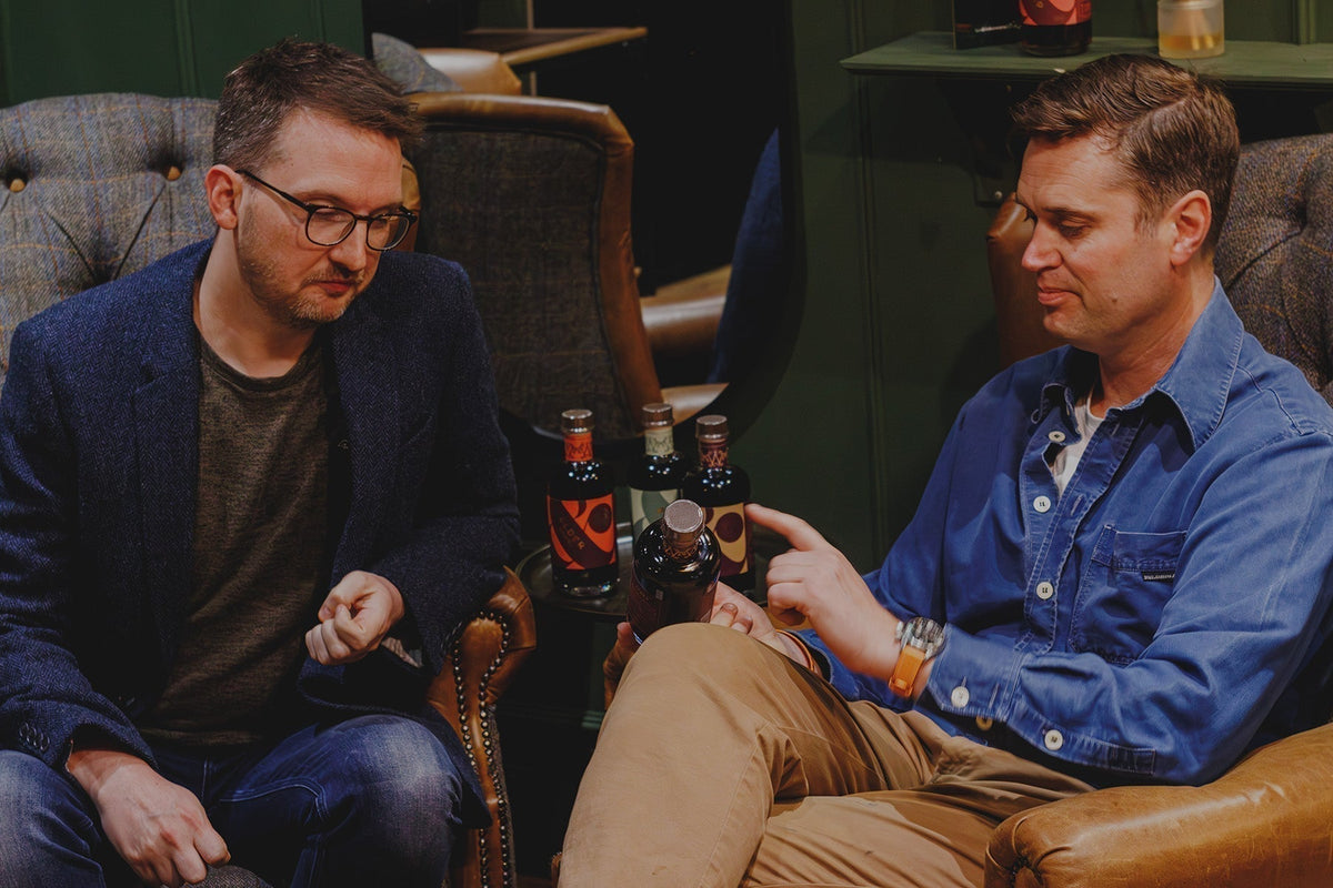 martin and tom sitting in a bar discussing their elderberry liqueur