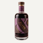 Bottle of Elder Black Forest by Wild & Wonder. In the bottle there is a dark liquid with a purple and dark purple label with gold lettering and a dark wooden stopper