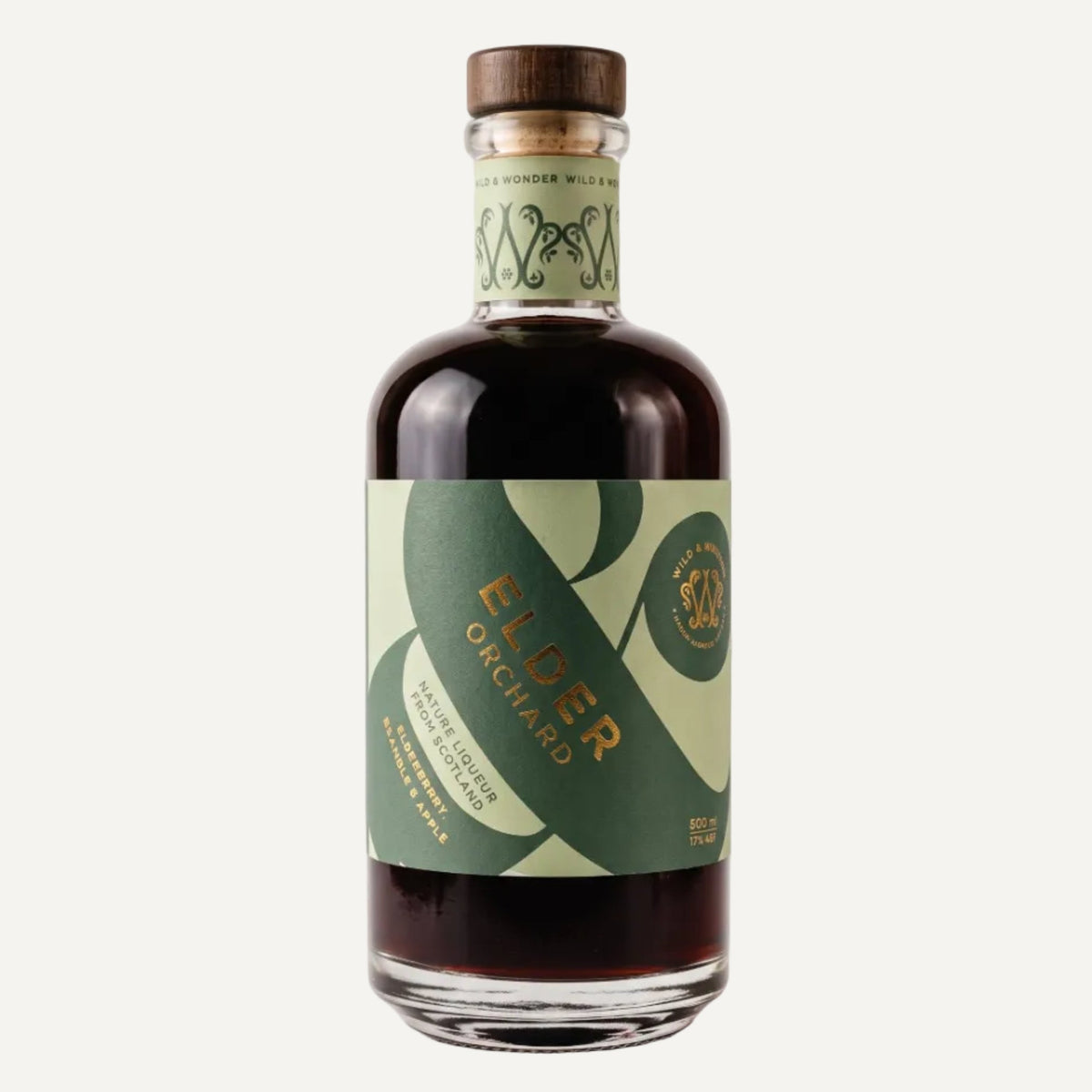 A bottle of Elder Orchard liqueur with a dark amber liquid, featuring a green and light green label with gold lettering and a brown wooden cap, set against a plain light grey background.