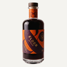 Bottle of Elder Spiced by Wild & Wonder. The bottle contains a dark liquid with an orange and purple label with gold foil detail and a dark brown wooden stopper