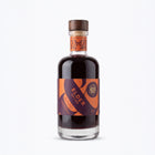 A 200ml bottle of Wild & Wonder Elder Spiced elderberry, ginger & orange liqueur with a dark amber liquid, dark purple and orange label and wooden stopper.