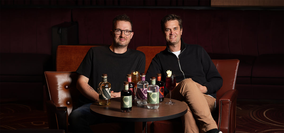 Wild & Wonder founders Tom and Martin in a bar booth with their liqueurs and vodkas