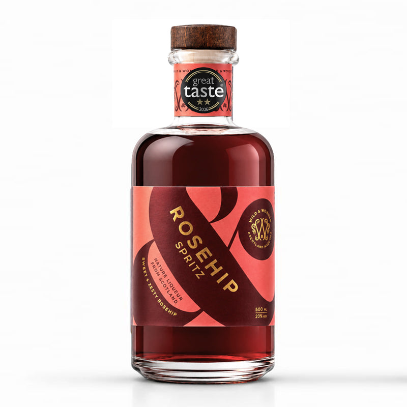 A bottle of Rosehip Spritz liqueur by Wild & Wonder, featuring a dark red liquid, a red and black label with gold lettering, and a wooden cap. A black 2 star 'great taste 2026' award badge is displayed on the neck of the bottle