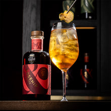A bottle of Wild & Wonder Rosehip Spritz set behind a glowing orange spritz cocktail in a luxury bar setting