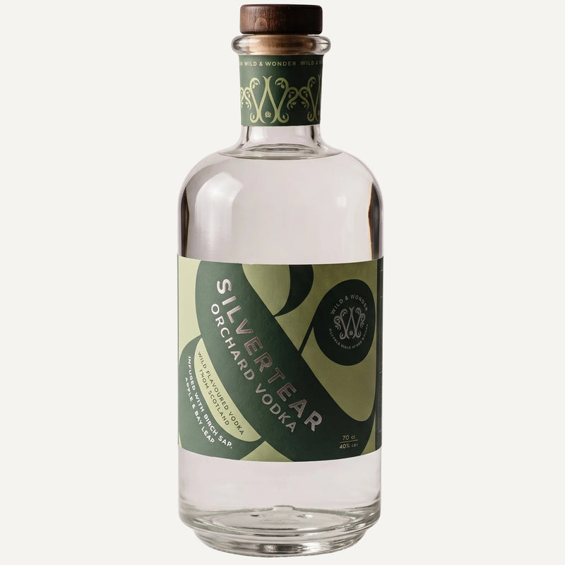 A bottle of Silvertear Orchard vodka with a green and beige label and dark wooden stopper, on a light grey background
