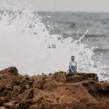A bottle of Silvertear Nature vodka on coastal rocks as a wave crashes behind it