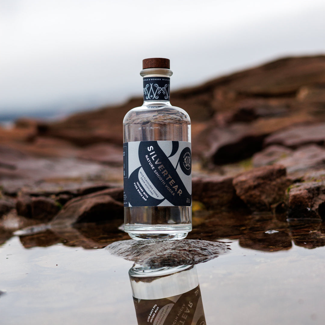 A bottle of Silvertear Nature vodka on the rocks, reflected in a rock pool