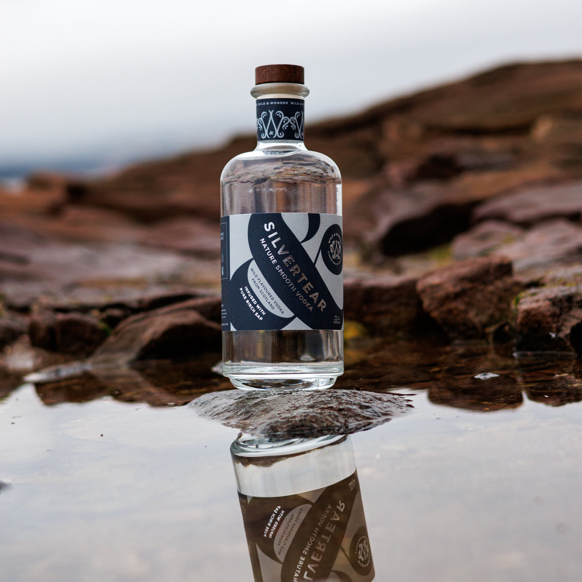 A bottle of Silvertear Nature vodka reflected in a rock pool