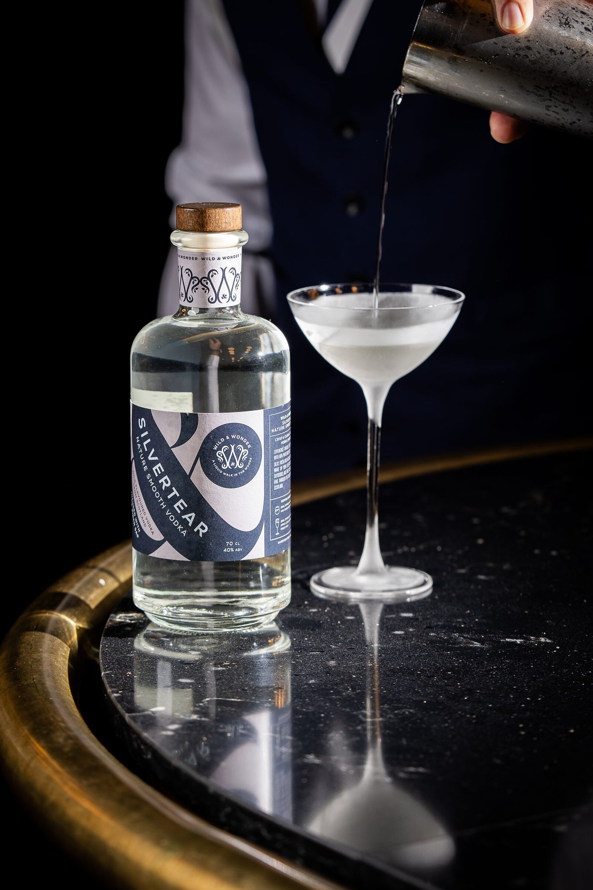 A martini being poured beside a bottle of Silvertear Nature vodka