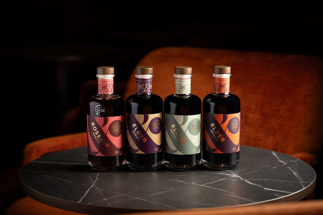 Four Wild & Wonder liqueurs lined up on a marble bar table